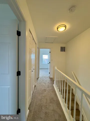 a view of a hallway with wooden floor and a bathroom