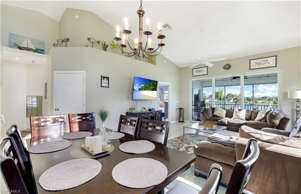 5928 Sand Wedge Lane, Unit 1808 Naples, FL 34110 - Photo 2 of 25 a dining room with wooden floor a chandelier fan a wooden table and chairs