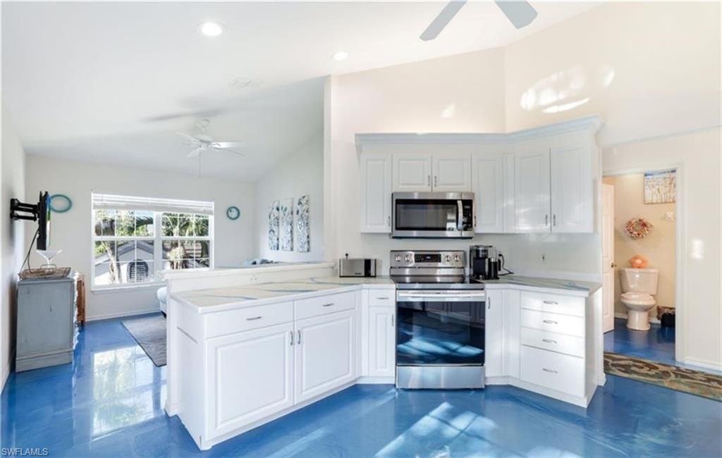 5928 Sand Wedge Lane, Unit 1808 Naples, FL 34110 - Photo 5 of 25 a kitchen with white cabinets stainless steel appliances and wooden floor