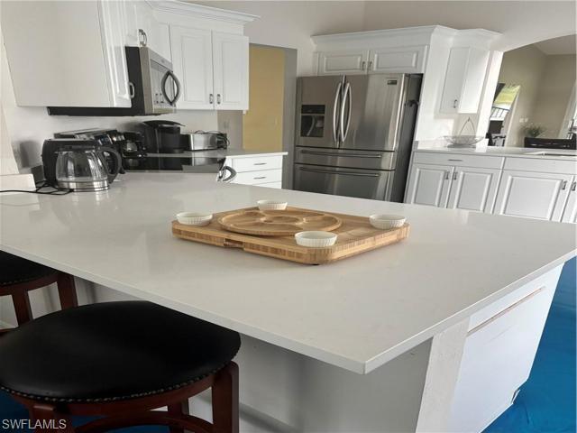 5928 Sand Wedge Lane, Unit 1808 Naples, FL 34110 - Photo 8 of 29 a kitchen with a refrigerator a stove a sink and a dining table
