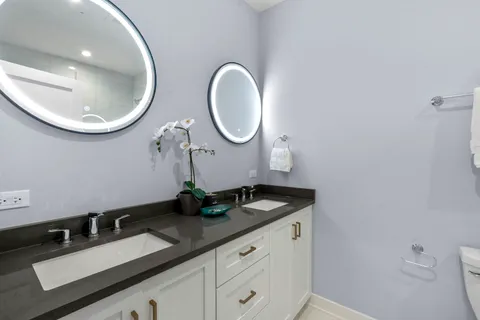 a bathroom with a granite countertop double vanity sink and a mirror
