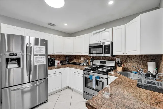 a dining room with stainless steel appliances kitchen island granite countertop a refrigerator and microwave