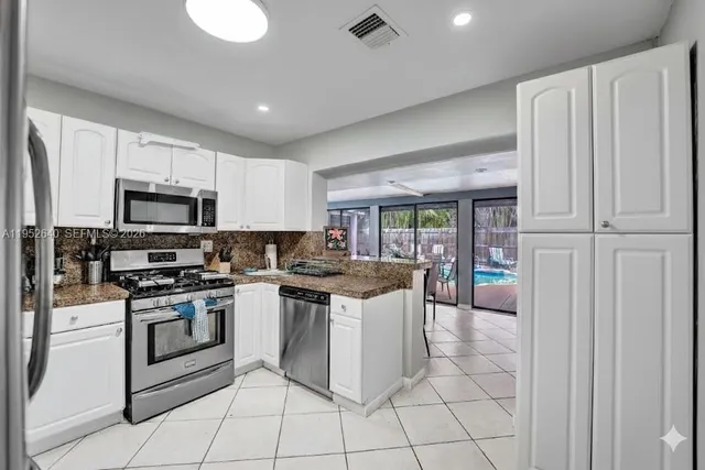 a kitchen with stainless steel appliances granite countertop a stove top oven a refrigerator and a sink