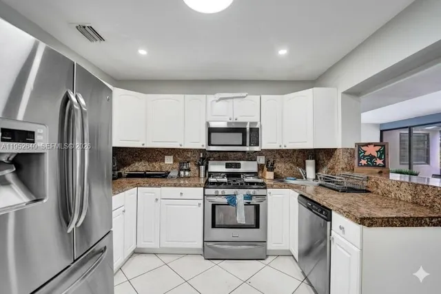 a view of a dining room with furniture one side kitchen view and wooden floor