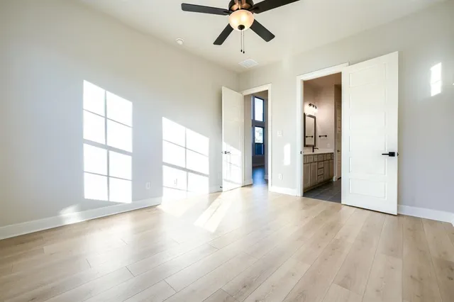 an empty room with wooden floor closet and windows