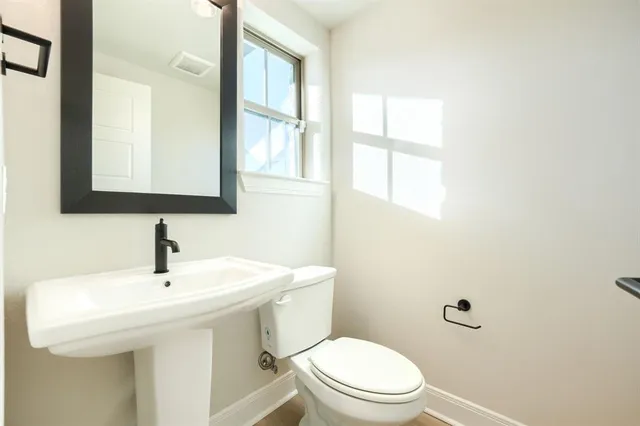 a bathroom with a toilet a sink a mirror and a window