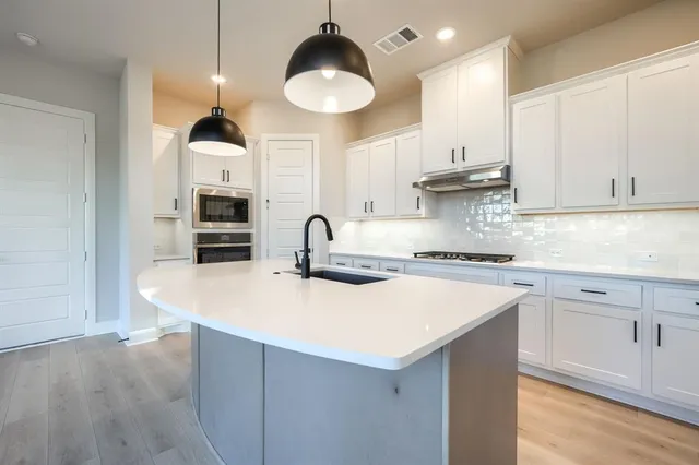 a kitchen with kitchen island granite countertop a sink a stove and cabinets