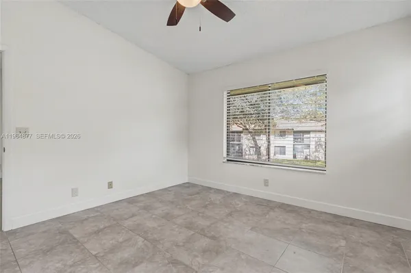 an empty room with chandelier fan and windows