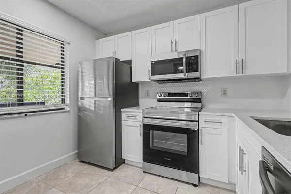a kitchen with cabinets stainless steel appliances and a window