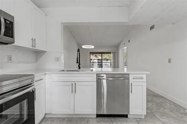 a kitchen with stainless steel appliances a stove and white cabinets