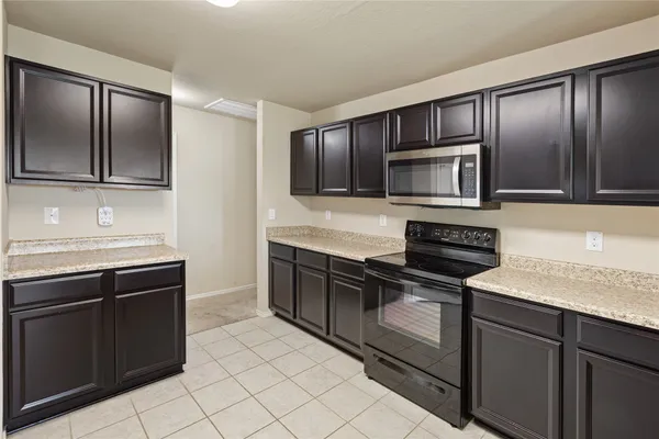 a kitchen with stainless steel appliances granite countertop a refrigerator a stove a sink a microwave and island