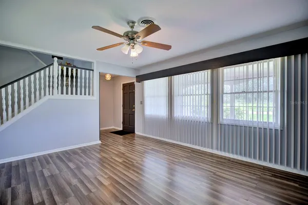 a view of empty room with wooden floor and fan
