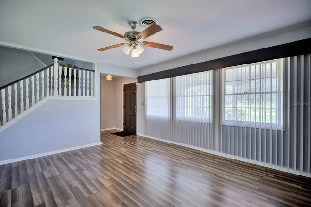 a view of empty room with wooden floor and fan