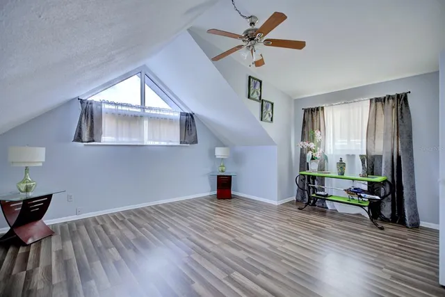 an empty room with wooden floor a ceiling fan and windows