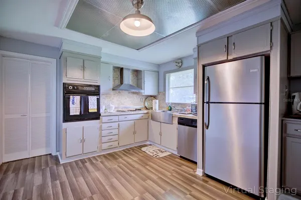 a kitchen with granite countertop stainless steel appliances a refrigerator cabinets and wooden floor