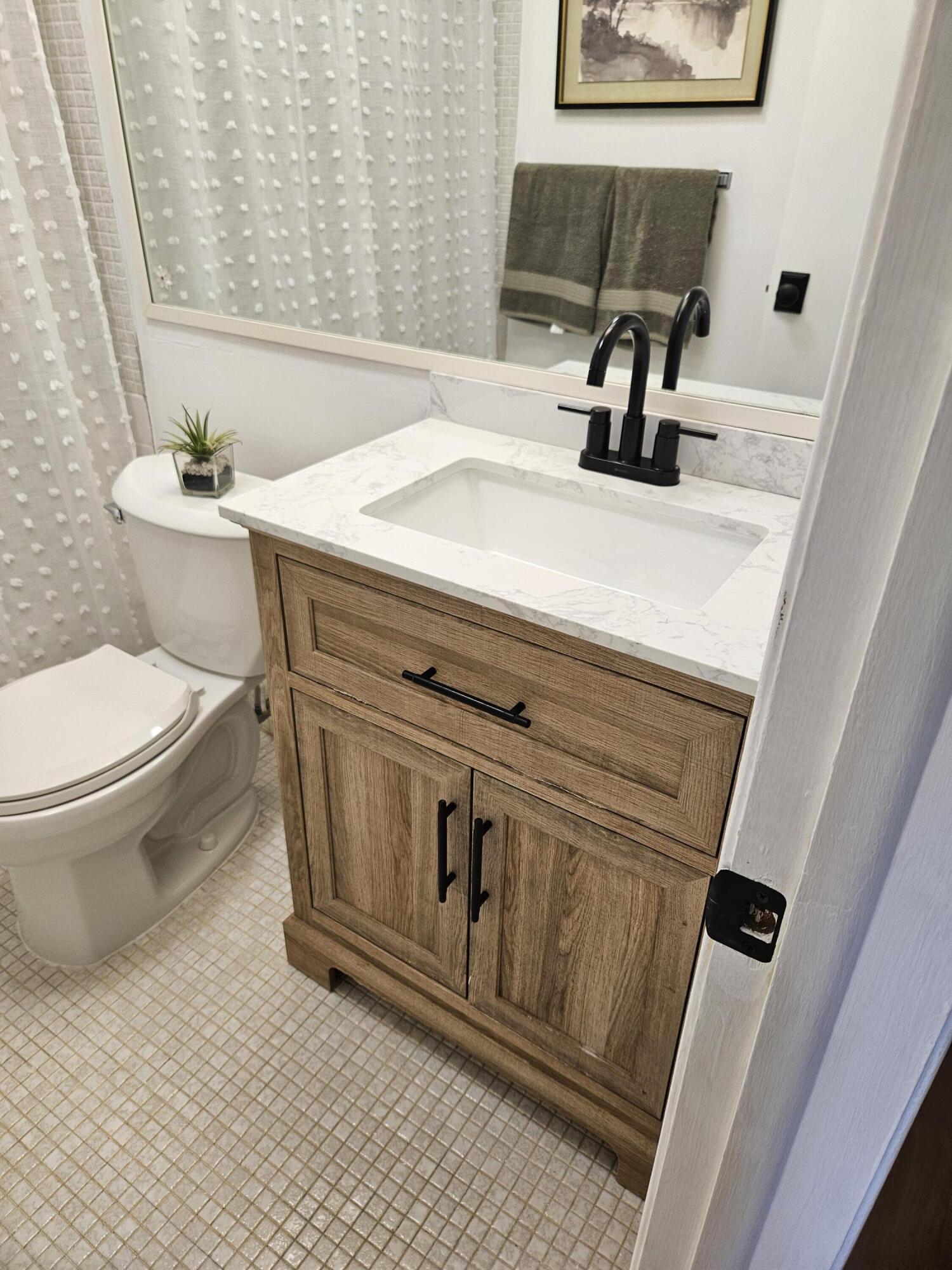 680 Horizon West, Unit 211 Boynton Beach, FL 33435 - Photo 3 of 6 a bathroom with a sink a toilet and mirror