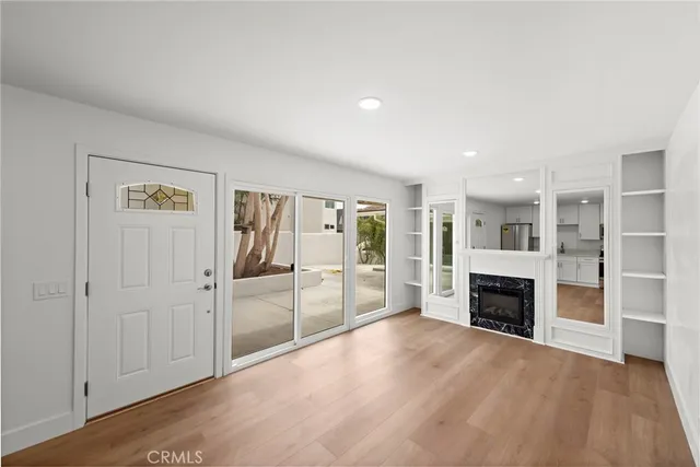 an empty room with wooden floor fireplace and cabinet