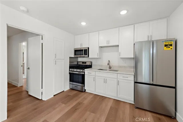 a kitchen with stainless steel appliances a refrigerator a stove a sink and white cabinets