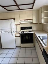 4824 Southwest 152nd Court, Unit 32G Miami, FL 33185 - Photo 9 of 24 a kitchen with a stove top oven and cabinets
