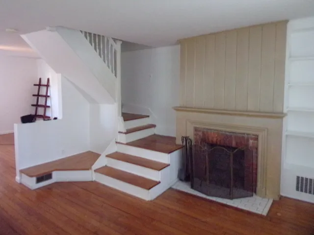 a view of a livingroom with wooden floor and a fireplace