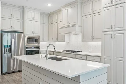 a kitchen with stainless steel appliances granite countertop a sink a stove and refrigerator