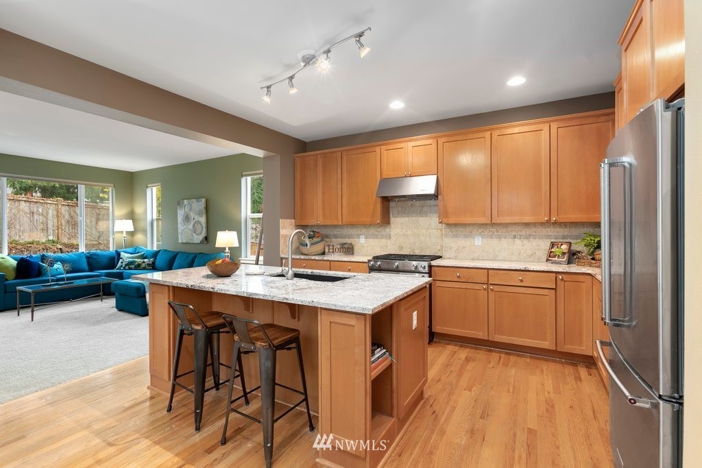 552 Mount Baker Place Northeast Renton, WA 98059 - Photo 6 of 25 a kitchen with stainless steel appliances granite countertop a refrigerator a sink dishwasher a stove and white countertops with wooden floor