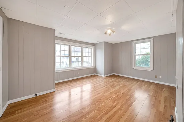 an empty room with wooden floor and windows