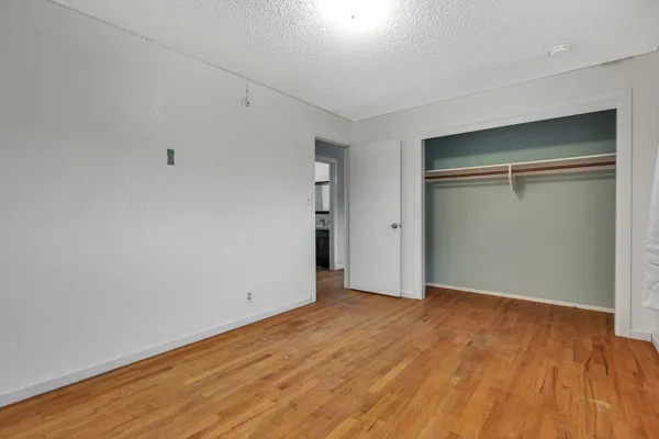 a view of an empty room with wooden floor & closet