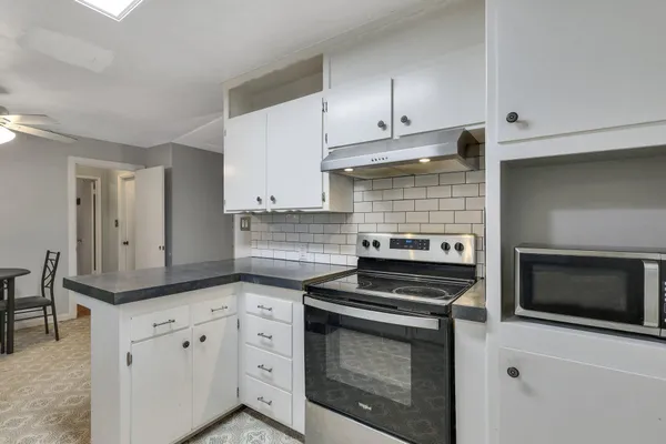a kitchen with granite countertop white cabinets and appliances