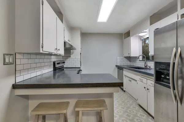 a kitchen with stainless steel appliances granite countertop a sink a stove and a refrigerator