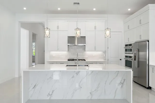 a large kitchen with stainless steel appliances kitchen island a large counter top a stove and a sink