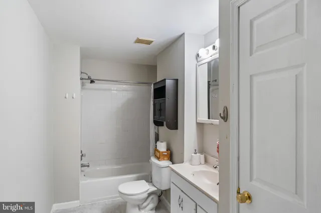a bathroom with a granite countertop bathtub shower sink vanity and toilet