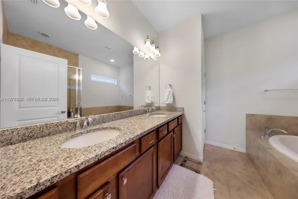 a bathroom with a granite countertop sink a large mirror and a bathtub