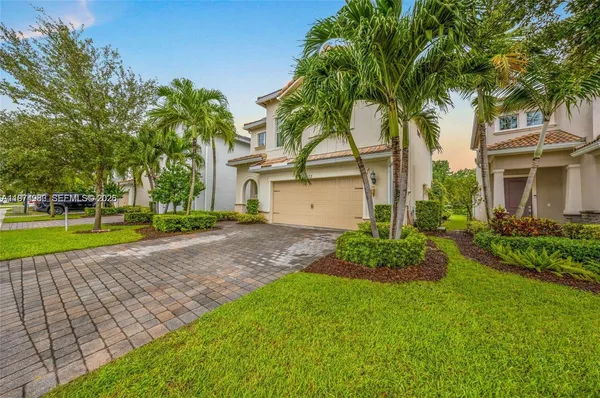 a view of a house with a yard and palm trees