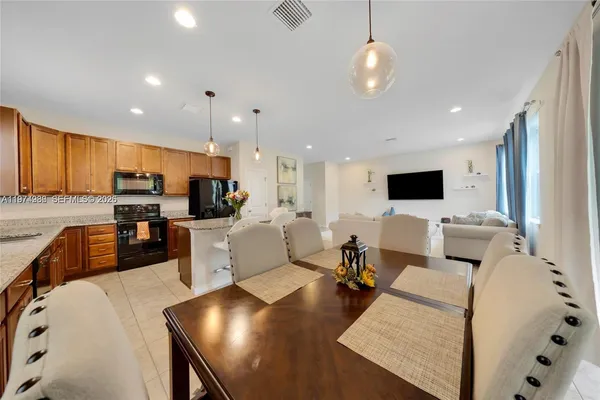a living room with furniture kitchen view and a wooden floor