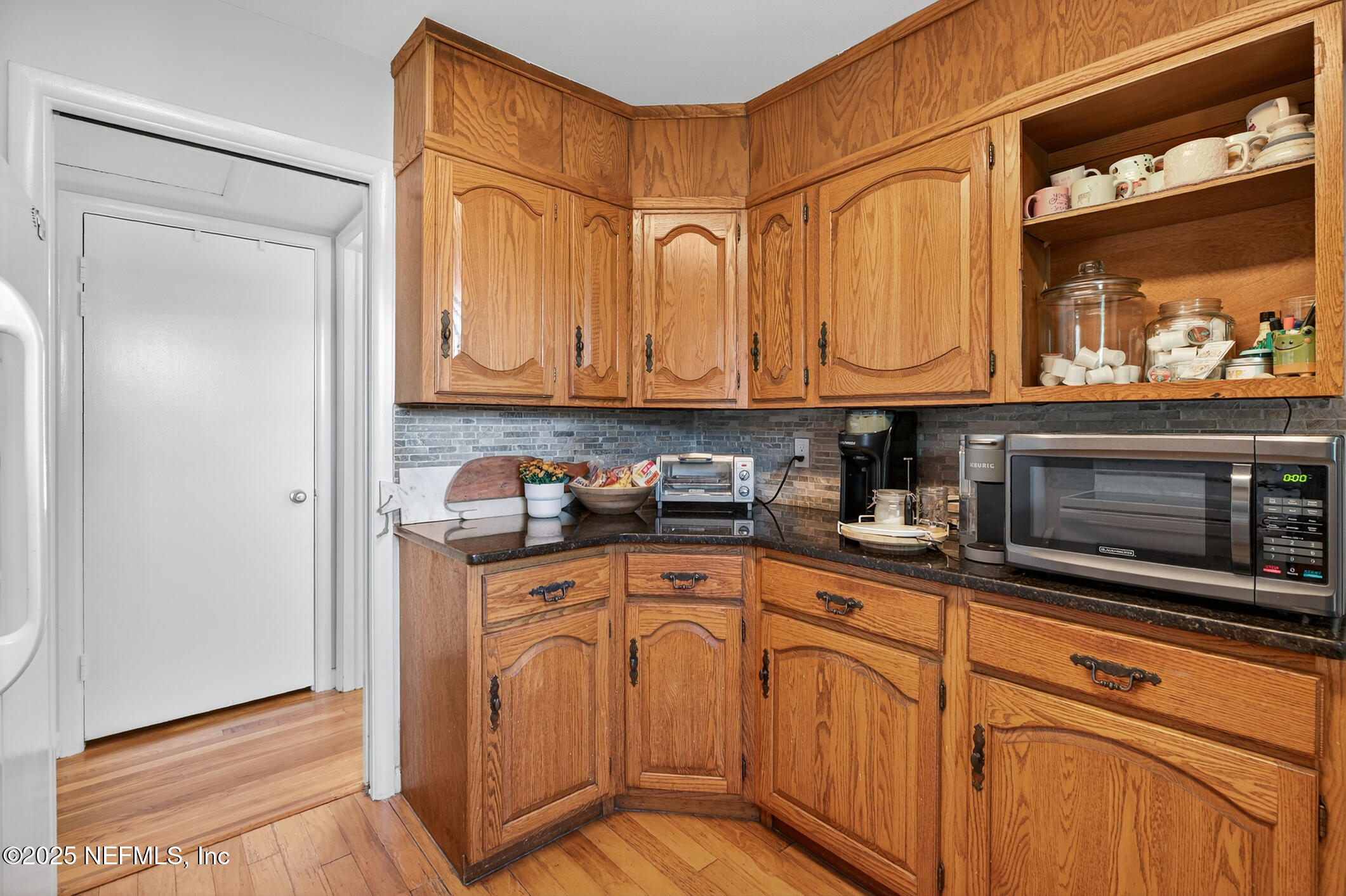 7470 Spinola Road Jacksonville, FL 32217 - Photo 32 of 76 a kitchen with stainless steel appliances granite countertop a refrigerator a oven and white cabinets with wooden floors