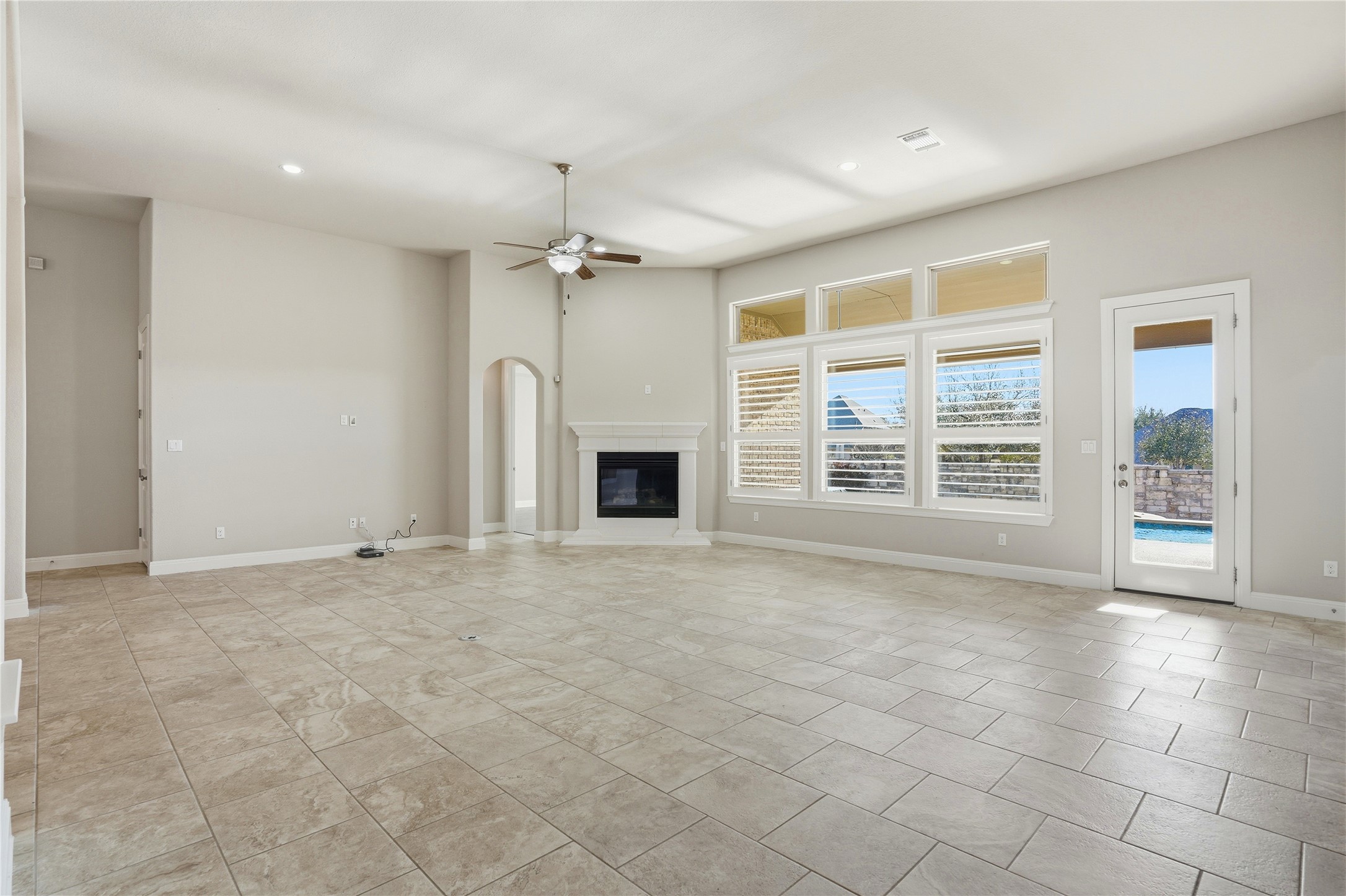 4109 Haight Street Round Rock, TX 78681 - Photo 11 of 40 Unfurnished living room with a ceiling fan, a glass covered fireplace, recessed lighting, and arched walkways