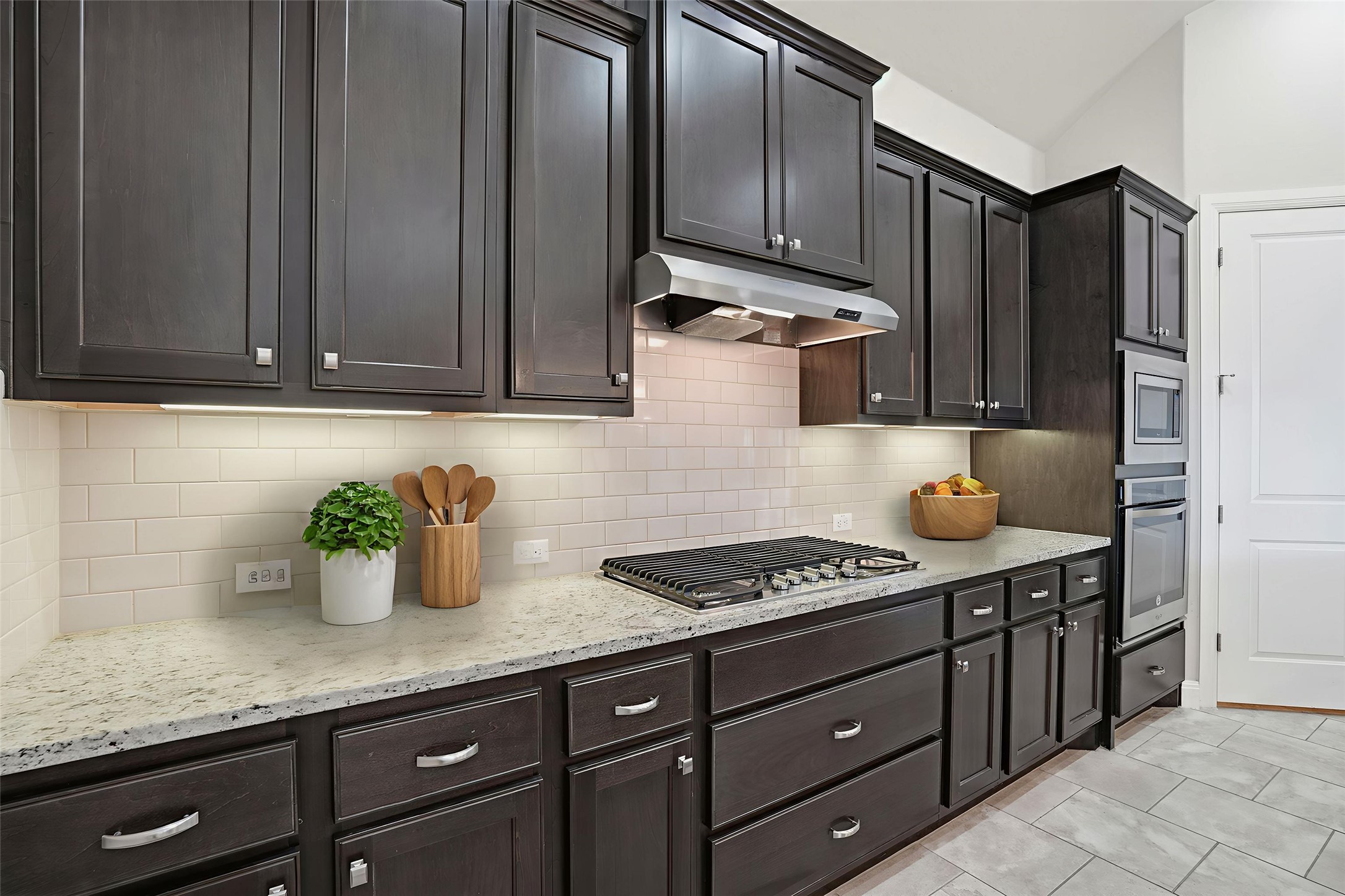 4109 Haight Street Round Rock, TX 78681 - Photo 7 of 40 Kitchen with light stone countertops, backsplash, stainless steel appliances, vaulted ceiling, and dark wood finish cabinetry