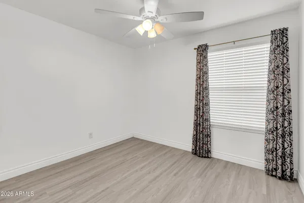 an empty room with wooden floor fan and windows