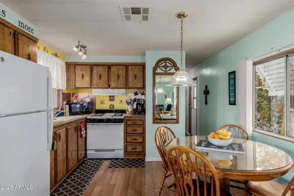a kitchen with stainless steel appliances granite countertop a stove refrigerator a dining table and chairs with wooden floor