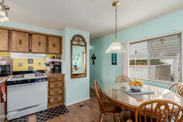 a kitchen with stainless steel appliances granite countertop a stove top oven a dining table and chairs with wooden floor