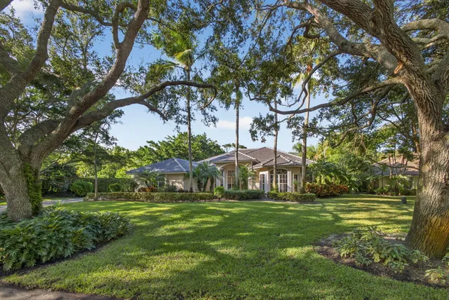 a view of a white house with a big yard and large trees