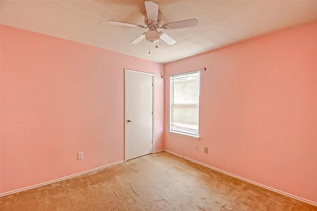 an empty room with windows and ceiling fan