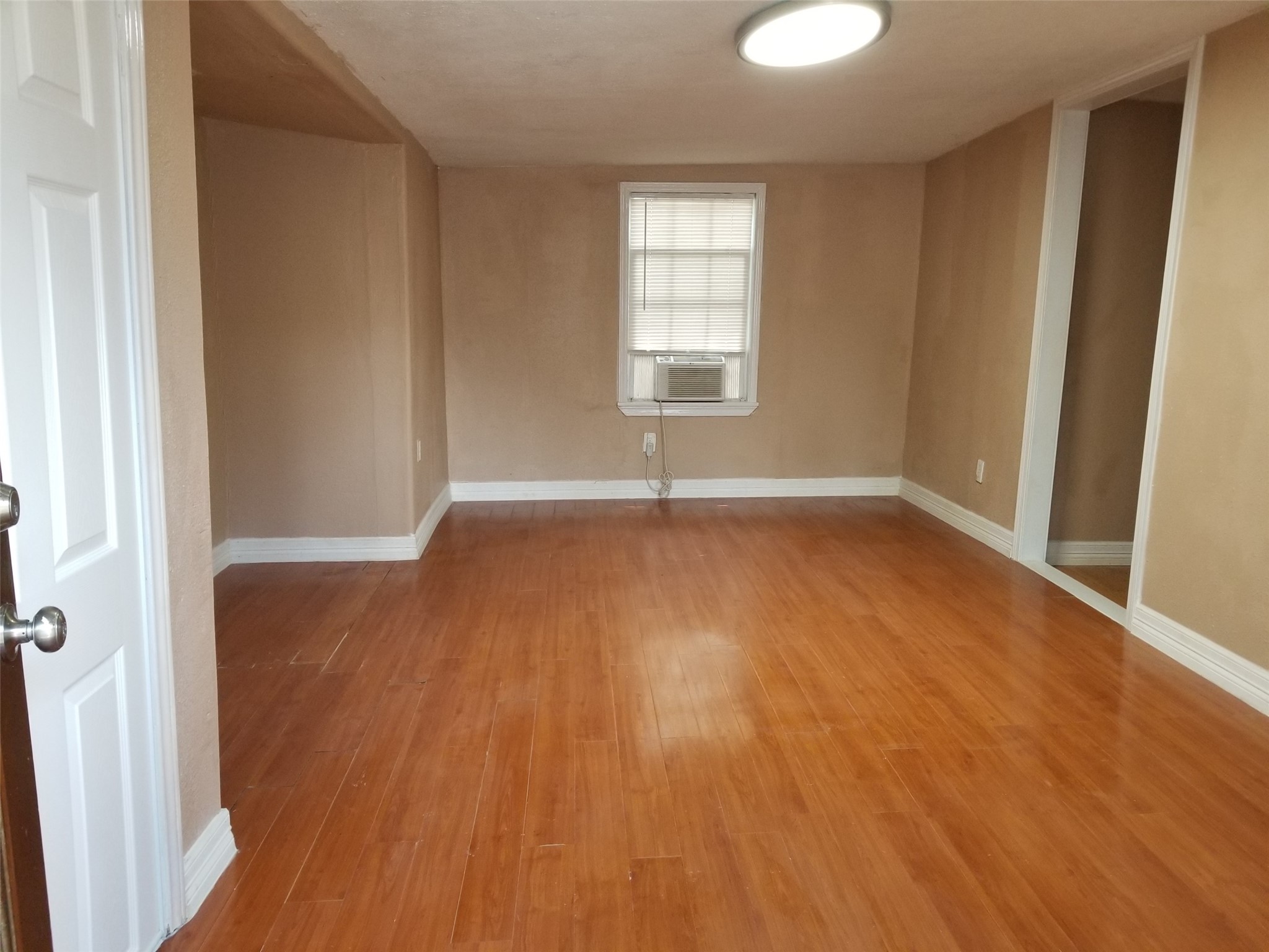 4714 Sharon Street Houston, TX 77020 - Photo 4 of 11 an empty room with wooden floor and windows