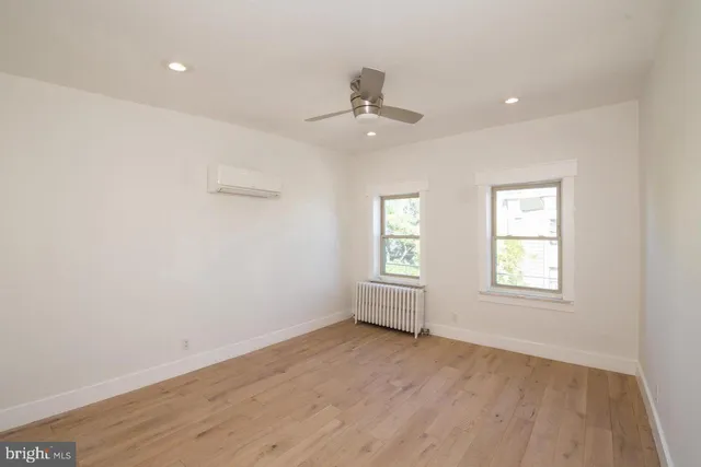 an empty room with wooden floor ceiling fan and windows