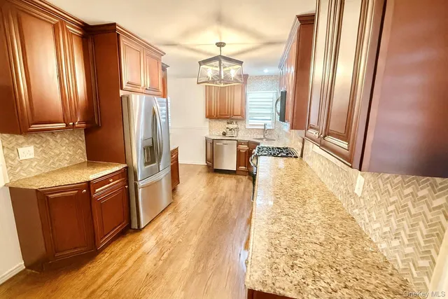 a kitchen with stainless steel appliances granite countertop a refrigerator a stove and a wooden cabinets