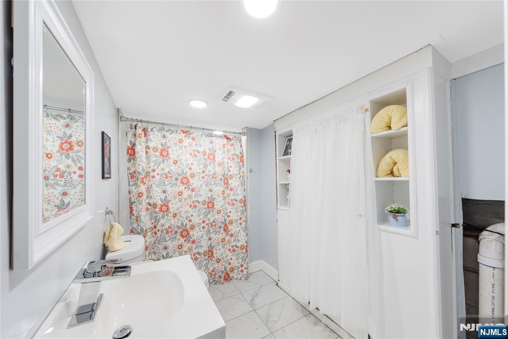 61-63 Keer Avenue Newark, NJ 07112 - Photo 21 of 33 a bathroom with a sink a toilet and shower curtain
