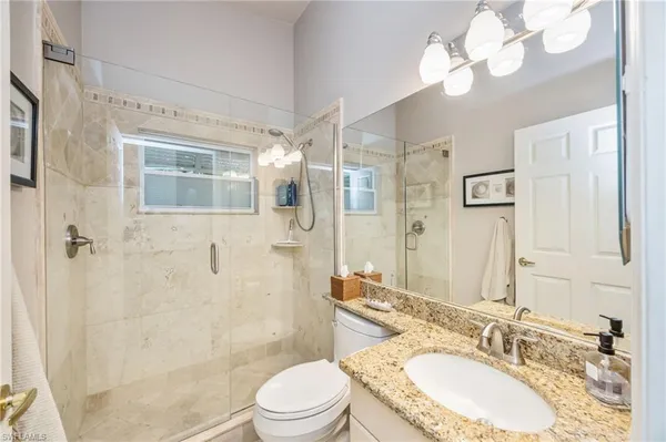 a bathroom with a granite countertop sink a toilet and a mirror