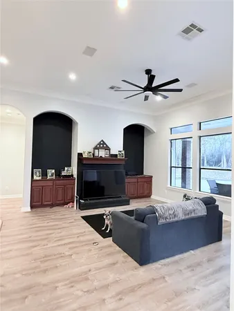 a living room with furniture a flat screen tv and a ceiling fan