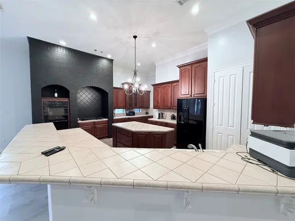 a kitchen with stainless steel appliances kitchen island granite countertop a refrigerator a sink and white cabinets with wooden floor